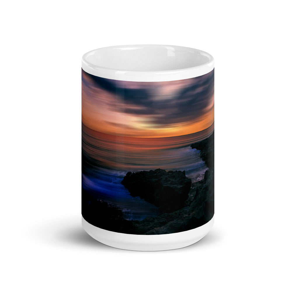 Weiß glänzende Tasse/Sonnenuntergang vor der felsigen Küste